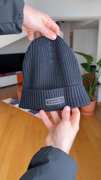 Black ribbed knit beanie with a rolled hem and a subtle Calvin Klein logo patch on the side. Soft texture and snug fit.