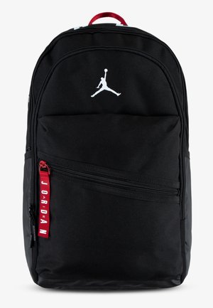 Black backpack made of nylon, featuring a white Jumpman logo, multiple zippered compartments, and a red pull tab with "JORDAN" text.