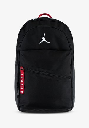 Čierny batoh vyrobený z nylonu, s bielym logom Jumpman, viacerými zipsovými priehradkami a červenou ťahajúcou páskou s textom "JORDAN".