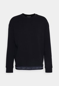 Svart sweatshirt med rund halsringning, sänkta axlar och ett kontrasterande logoband längs nederkanten i blå text. Mjuk bomullsmaterial.