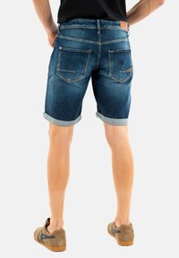 Pantalones cortos de denim en azul oscuro con dobladillos enrollados, que cuentan con dos bolsillos traseros, una etiqueta de cuero en la cintura y un corte clásico.
