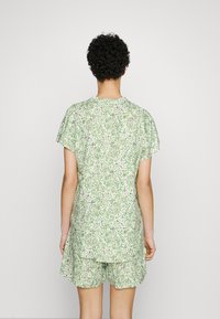 Completo floreale verde composto da una maglietta ampia con maniche corte e pantaloni corti abbinati, realizzato in tessuto leggero con un motivo testurizzato.
