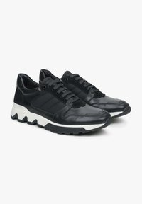 Czarne sneakersy wykonane z leathers i tkaniny, charakteryzujące się smukłym designem, teksturowanymi panelami, zaokrąglonym noskiem oraz białą gumową podeszwą z wzorem w zygzak.