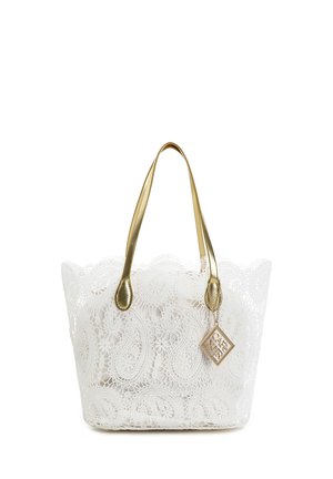 Sac cabas en dentelle blanche avec un motif cachemire complexe, anses dorées et un pendentif carré en or suspendu à une bandoulière.