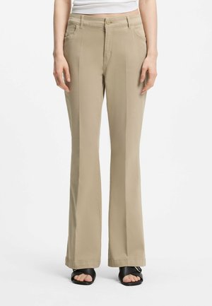 Pantaloni beige a vita alta e gamba dritta, indossati con sandali neri con punta aperta e un top bianco corto, mostrati dalla vita ai piedi.