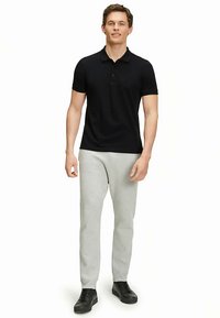 Czarna koszulka polo, szare dresy i czarne trampki. Polo ma klasyczny kołnierzyk i trzy guziki. Dresy są casualowe i dopasowane.