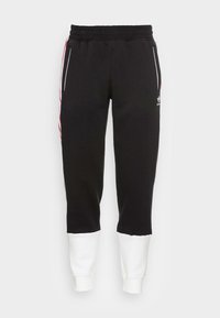 Pantaloni della tuta neri con elastico in vita, polsini bianchi e strisce laterali rosse. Presenta un logo ricamato in bianco sulla gamba sinistra. Materiale morbido.