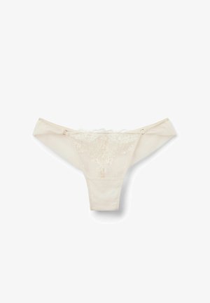 Beige Tanga mit Spitzenrand und floralem Stickerei auf der Vorderseite, aus weichem Material und mit zartem gewelltem Rand. Verfügt über einen seitlichen Verschluss.