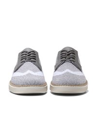 Zapatos de tela grises con un patrón zigzagueante blanco en contraste, detalles de cuero en los laterales y una suela de goma de color claro.