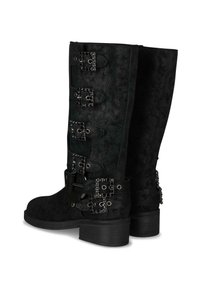 Botas negras de media caña con tacones cuadrados, decoradas con cuatro hebillas ornamentadas que presentan cuentas negras en los lados exteriores.