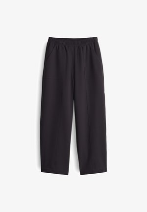 Schwarze, weit geschnittene Hosen aus glattem Stoff. Mit elastischem Bund und zwei Seitentaschen, versehen mit sichtbaren Nähdetails.