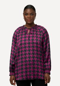 Bluse i lilla og sort houndstooth-mønster med nøglehul-halsudskæring, elastiske manchetter og en samlet halsudskæring for en løs pasform.