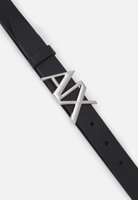 Cinturón de cuero negro con una elegante hebilla geométrica plateada que presenta un diseño angular y estilizado. Correa texturizada con agujeros ajustables.