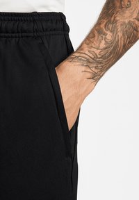 Zwarte jogginbroeken met een elastische tailleband en zijzak, met een gladde stofstructuur en een getailleerd ontwerp.