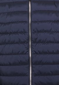Navy puffer vest med horisontal quilted design, fuld lynlås med metalliske tænder, glat tekstur, letvægts og isoleret.