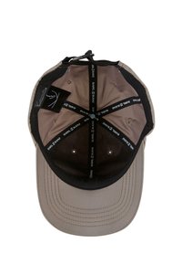 Baseball caps med khaki utside, svart skjerm og kontrasterende svart indre fôr. Har ventilasjonshull og merkede innvendige etiketter.