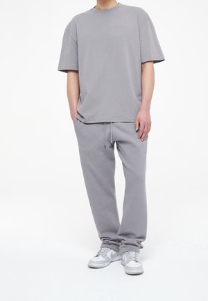 T-shirt grigio in cotone a maniche corte e vestibilità comoda, abbinato a pantaloni jogger grigi coordinati con vita elastica e coulisse.