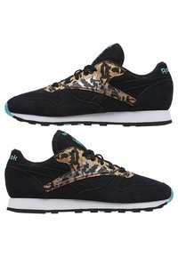 Paire de baskets noires Reebok avec des accents imprimé léopard, des détails turquoise, des semelles intermédiaires blanches et des semelles extérieures noires, vues de profil.