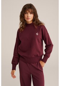 Felpa bordeaux con collo alto, orlo a coste e maniche con polsini. Presenta un piccolo logo sul petto ed è realizzata in tessuto morbido.