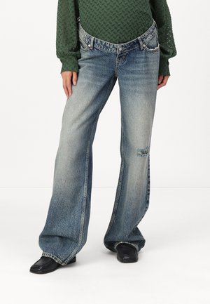 Light blue denim flared jeans with a faded finish, a slight rip on the knee, and silver hardware on the pockets. Classic five-pocket design.