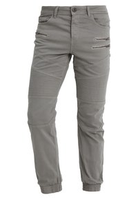 Grau tapered Hosen aus Baumwollmischung. Mit Reißverschlusstaschen, gerippten Akzenten an den Knien und elastischen Bündchen an den Knöcheln.
