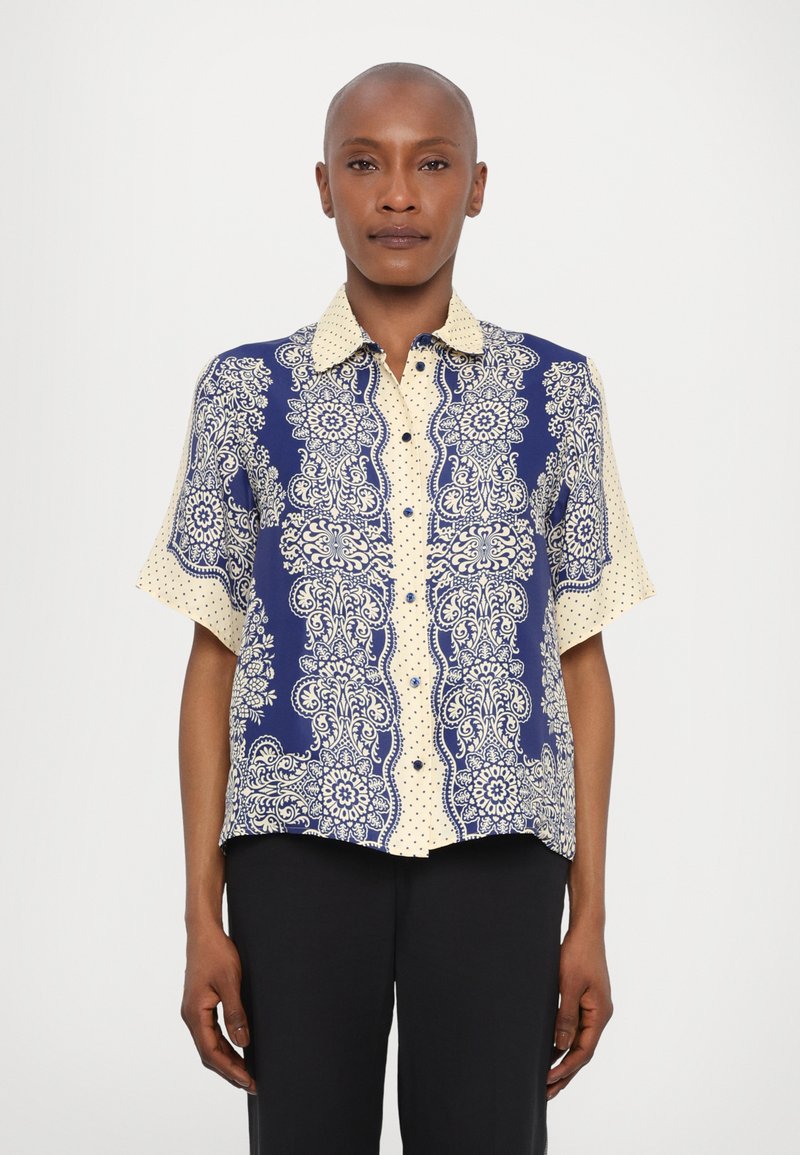 Camicia a maniche corte con un motivo paisley blu e crema con pois, bottoni sul davanti e colletto. 