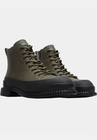Botas impermeables verde oliva con puntera de goma y suela negra texturizada, que cuentan con un diseño de cordones y una cremallera lateral para un uso fácil.