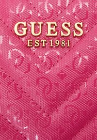 Portafoglio rosa testurizzato con motivo a zigzag, con logo dorato "GUESS" e dettagli "EST 1981". Finitura liscia e lucida.