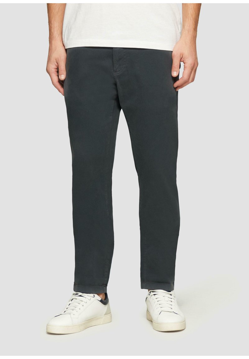 Donkergrijze chino's met een rechte pasvorm, gemaakt van zachte stof, gecombineerd met witte sneakers met zwarte accenten.