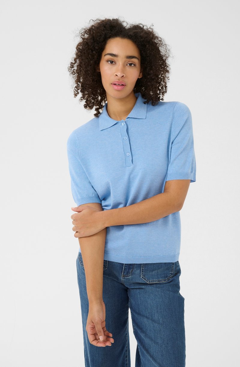 Lichtblauw polo shirt met korte mouwen en een kraag, voorzien van een sluiting met drie knopen, zachte textuur en een relaxte pasvorm, gestyled met blauwe denim.