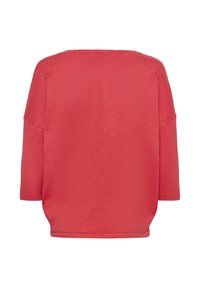 Pull corail surdimensionné avec manches trois-quarts, surface texturée et un design simple. Ourlet droit et détail de couture au dos.