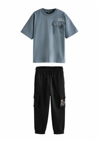 Graues Baumwoll-T-Shirt mit kurzen Ärmeln und einer Brusttasche. Schwarze Jogginghose mit elastischem Bund und Cargo-Taschen.