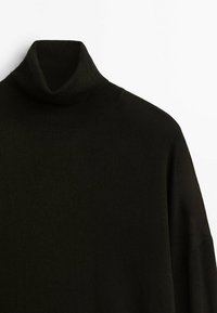 Czarny golf wykonany z dzianiny prążkowanej, z wysokim kołnierzem i luźnym krojem o gładkiej fakturze.