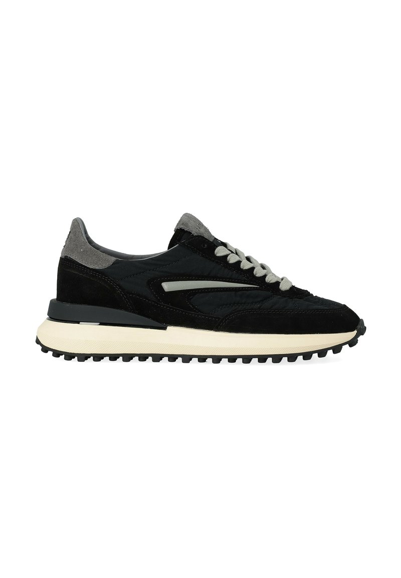 Sneaker nera e grigia con tomaia in suede e tessuto, caratterizzata da uno strato testurizzato, lacci grigio chiaro e una spessa suola in gomma bianca.