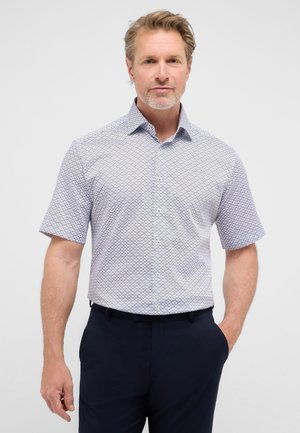 Chemise à manches courtes de couleur bleu clair avec un motif géométrique, col boutonnière et coupe décontractée, assortie à un pantalon sombre.