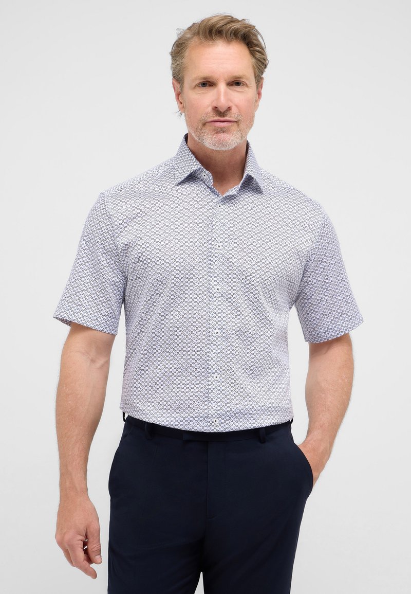 Korte mouwen shirt in lichtblauw met een geometrisch patroon, met een button-down kraag en een ontspannen fit, gecombineerd met donkere broeken.