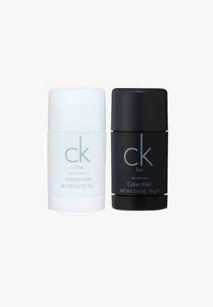 Hvide og sorte cylindriske deodorantstænger med skruelåg, mærket "ck one" og "ck be", begge 75 g, med en slank mat finish.