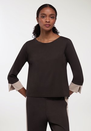 Top nero con maniche a tre quarti e polsini beige. Tessuto morbido, scollatura rotonda e vestibilità comoda. Design minimalista.