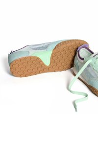 Zapatillas deportivas en azul claro y verde menta con una suela de goma texturizada, paneles de malla y acentos morados; los cordones son de color verde menta.