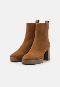 Ruske nubuk ankle boots med firkantet tå, stablet hæl og en trækflik bagpå for nem påklædning. Tekstureret sål og elegant design.