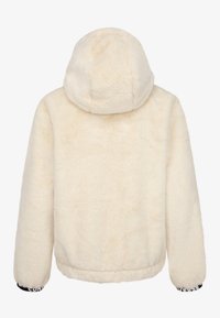 Kremowy sztuczny futerko z kapturem, charakteryzujące się miękką teksturą oraz elastycznymi mankietami z wzorzystymi akcentami na nadgarstkach.