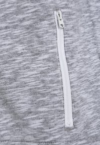 Gray athletic fabric features a smooth, slightly textured surface with a white zippered pocket on the side for secure storage.