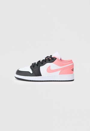 Niski sneaker z czarnymi, białymi i różowymi panelami, czarnymi sznurówkami, różowym logo Nike i białą podeszwą z czarnym bieżnikiem na jednolitym tle.