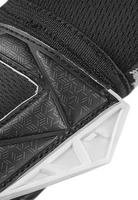 Schwarze Textilien und Gummi-Sportausrüstung mit geometrischen Mustern und weißen Akzenten. Das Design umfasst strukturierte Oberflächen und markante Formen.