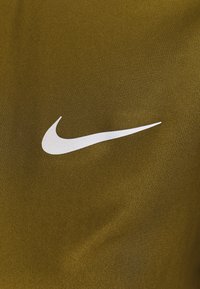 Grön idrottströja med en vit Nike-swoosh-logotyp. Tyget har en slät, strukturerad yta.