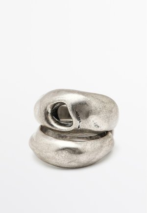 Bague en métal ornée de formes sculpturales irréguli�ères de couleur argentée. Présente une surface texturée et une fente ouverte sur la partie supérieure.