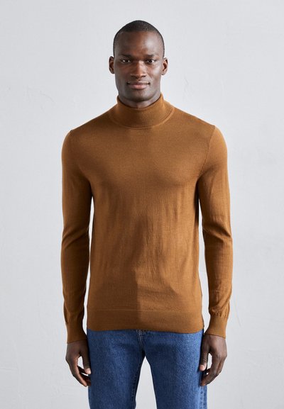 Pull en col roulé marron en matière douce, avec des manches longues et une coupe ajustée, associé à un jean en denim bleu.