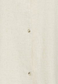 Tissu en lin beige avec une texture de tissage visible et deux petits boutons ronds et translucides alignés verticalement.