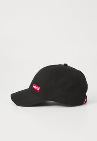 Căciulă de baseball din bumbac negru, cu o margine curbată, având un patch cu logo-ul roșu Levi's pe față și un tag mic pe lateral.
