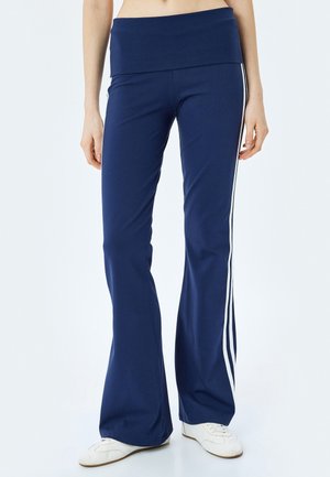 Navy blue flared pants with a wide waistband, featuring white side stripes. Made of stretchy fabric for comfort and mobility.